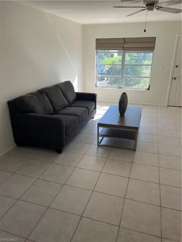 Living area featuring light tile patterned floors, ceiling fan, and baseboards