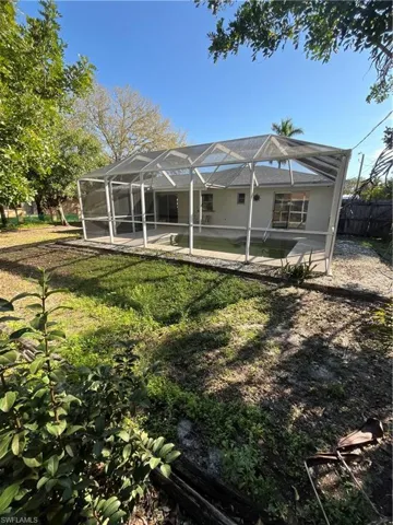 Rear view of property with glass enclosure, a patio area, fence, and a fenced in pool