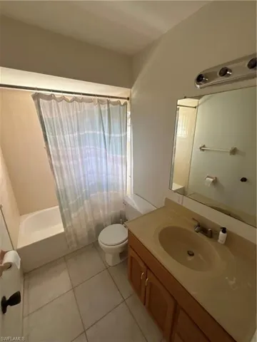 Full bathroom featuring toilet, shower / bathtub combination with curtain, vanity, and tile patterned floors