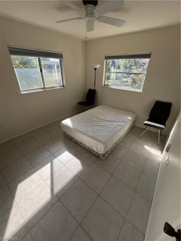 Unfurnished bedroom with tile patterned flooring, a ceiling fan, and baseboards