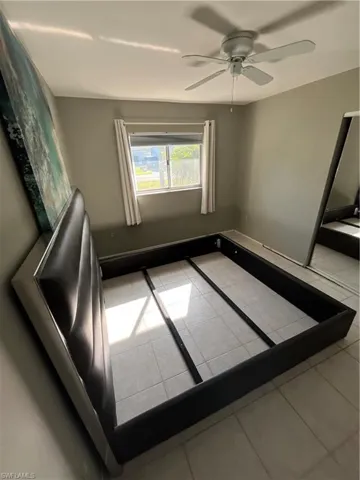 Tiled spare room featuring ceiling fan