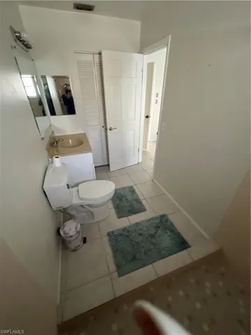 Bathroom featuring toilet, a sink, visible vents, and tile patterned floors