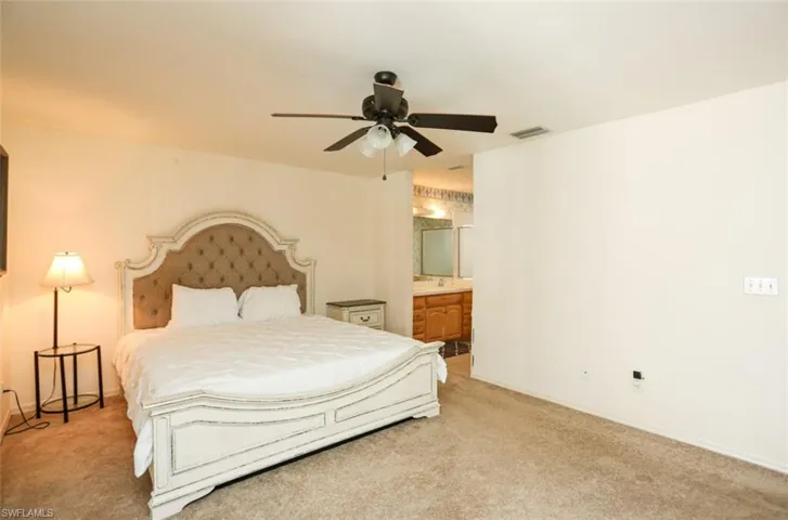 Carpeted bedroom with ceiling fan and ensuite bath