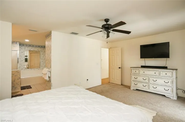 Bedroom with connected bathroom, ceiling fan, and light carpet