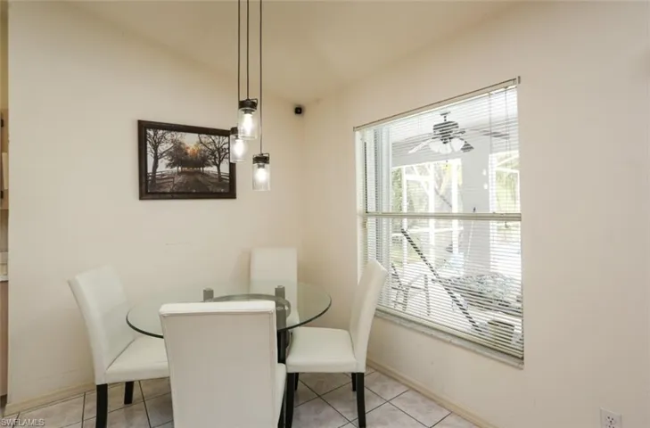 Dining space with ceiling fan, light tile patterned flooring, and vaulted ceiling