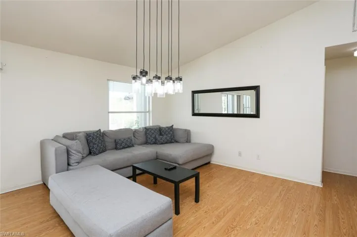 Living room with light hardwood / wood-style floors and vaulted ceiling