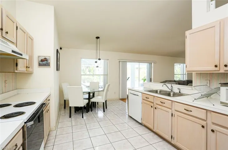 Kitchen featuring pendant lighting, white appliances, sink, and light brown cabinetry