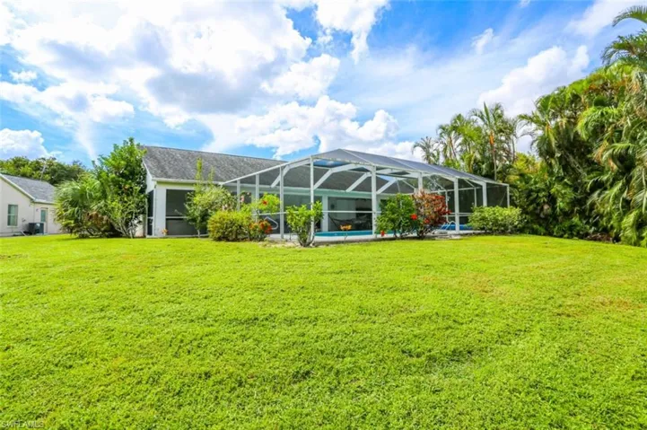 Back of house featuring a lanai, a yard, and a swimming pool