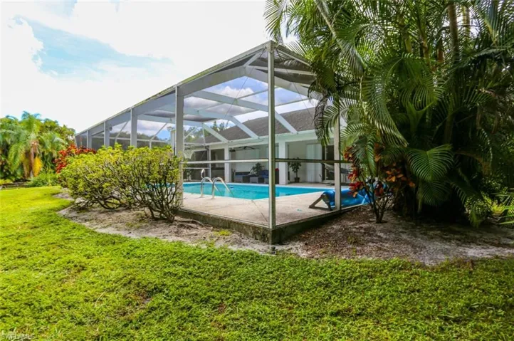 View of pool with glass enclosure and a yard
