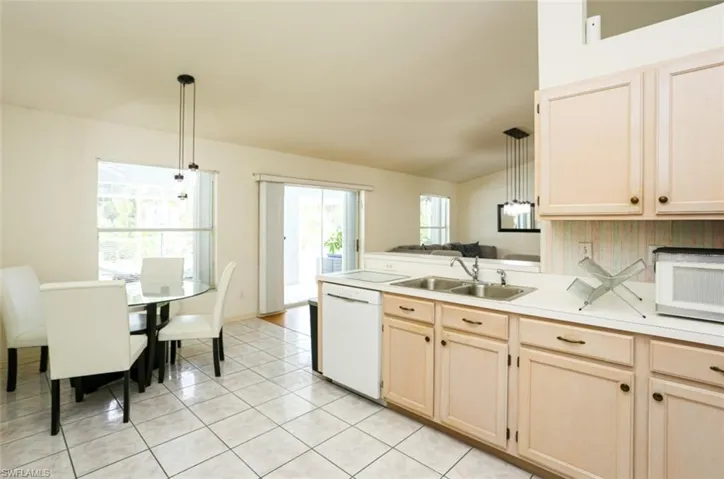 Kitchen featuring light tile patterned flooring, pendant lighting, white appliances, and sink