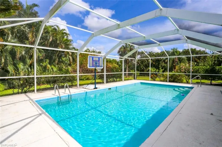 View of swimming pool featuring glass enclosure and a patio area