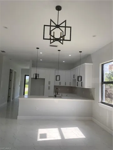 Kitchen featuring light marble finish flooring, white cabinetry, recessed lighting, light countertops, and pendant lighting