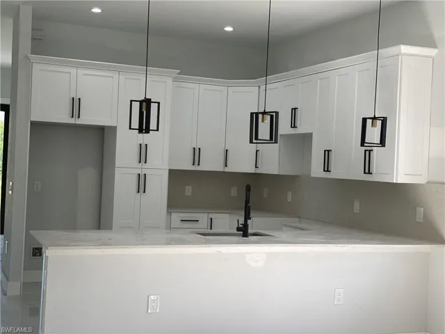 Kitchen featuring a peninsula, white cabinetry, recessed lighting, and light stone countertops