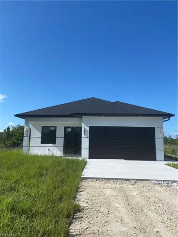 View of front facade featuring dirt driveway and an attached garage