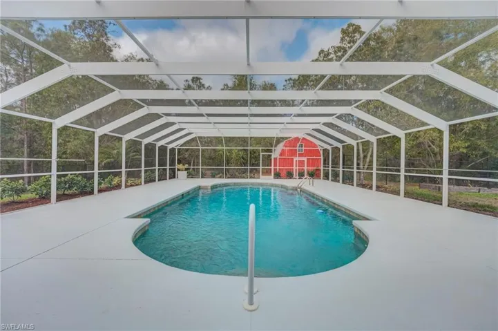 Swimming pool with glass enclosure, a sunroom, and a fenced backyard