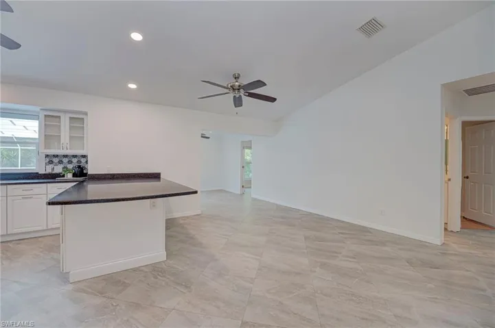 Kitchen featuring glass insert cabinets, a ceiling fan, white cabinetry, healthy amount of natural light, and recessed lighting