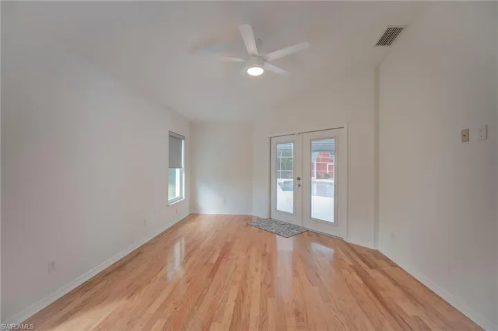 Spare room with french doors, light wood-style flooring, a ceiling fan, and plenty of natural light