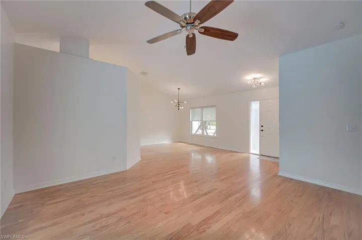 Spare room featuring suspended lighting, light wood-style flooring, and ceiling fan