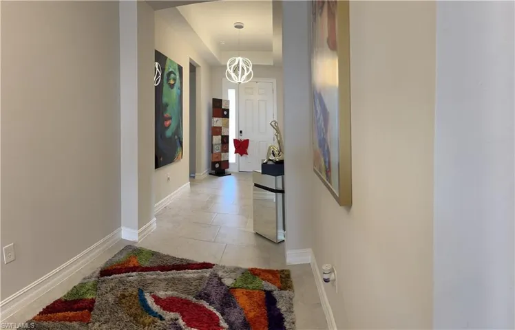 Hallway featuring light-toned tile flooring, recessed lighting, and a contemporary pendant light fixture
