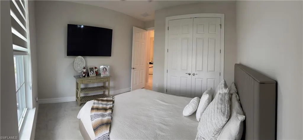 Room featuring light gray wall paint, a built-in wall-mounted television, and light-toned flooring