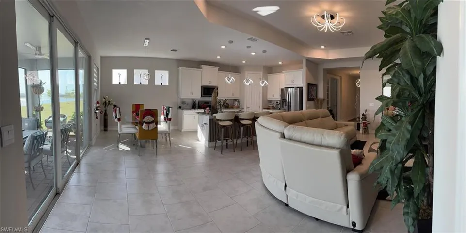 Open-concept living space featuring large format tile flooring, recessed lighting, and a contemporary chandelier