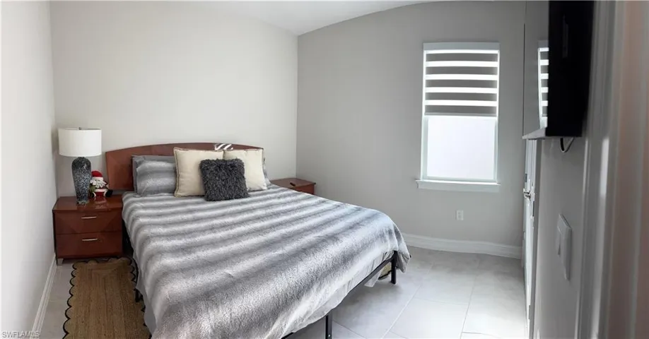 Bright room featuring a window with integrated blinds, tile flooring, and light-toned wall paint