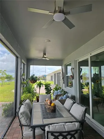 Screened outdoor living area with brick paver flooring, multiple ceiling fans, and large glass sliding doors