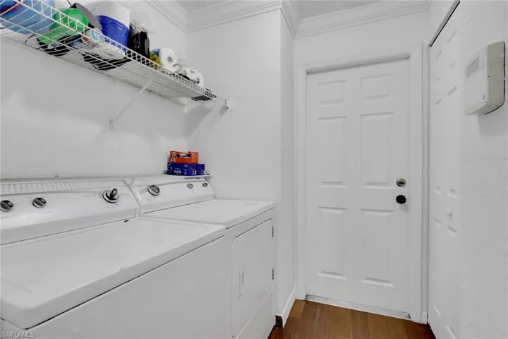 Washroom with independent washer and dryer, crown molding, and dark wood-type flooring
