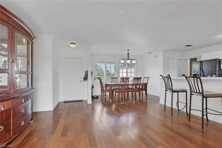 Dining space with dark wood-style floors and ornamental molding