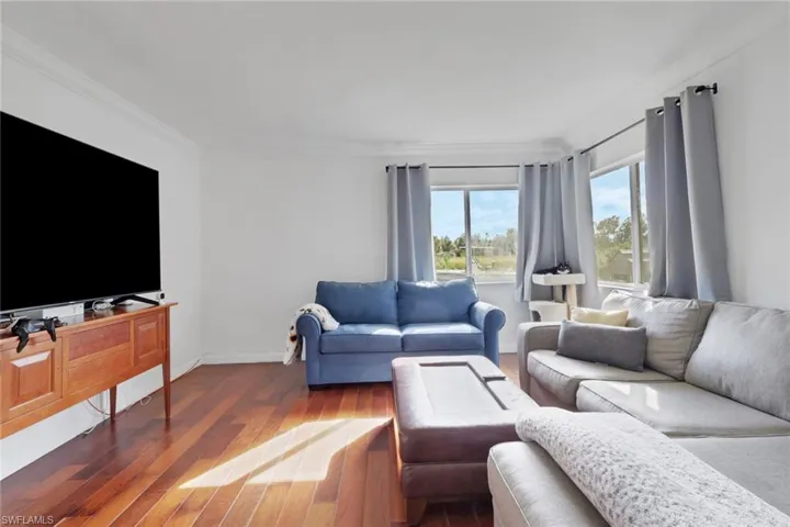 Living room featuring wood-type flooring and crown molding