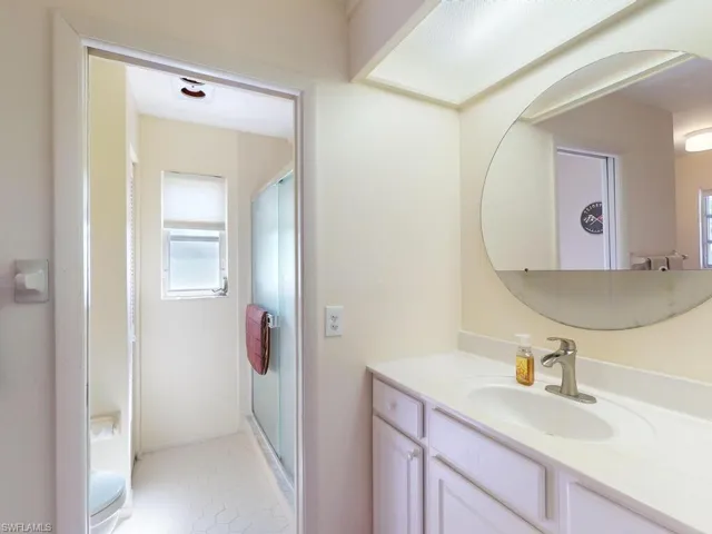Bathroom featuring vanity, toilet, an enclosed shower, and tile patterned flooring