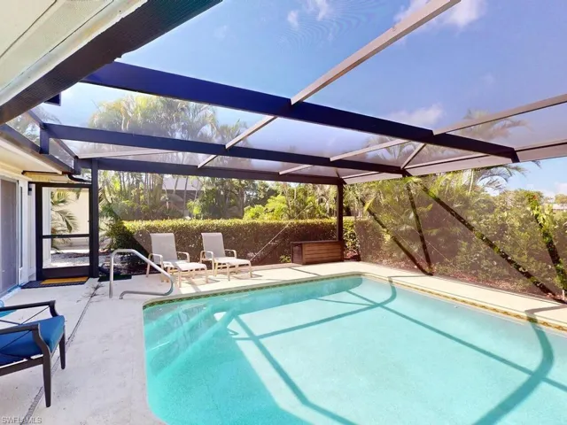 View of swimming pool featuring glass enclosure and a patio