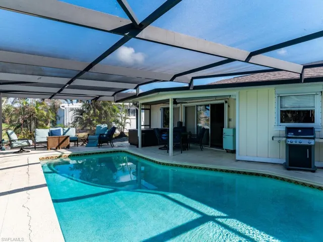 View of pool featuring an outdoor living space, area for grilling, a patio, and a lanai