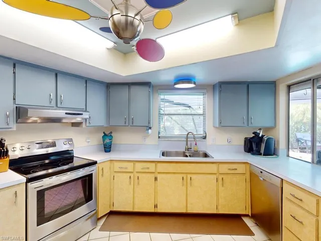 Kitchen with a tray ceiling, light tile patterned floors, stainless steel appliances, and sink