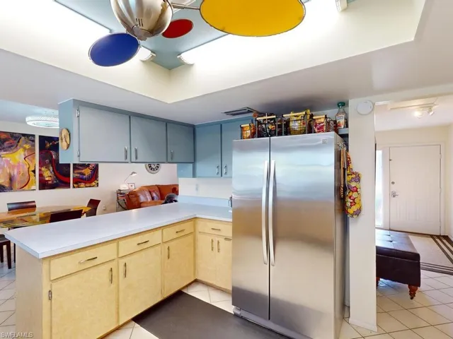 Kitchen featuring stainless steel fridge, light tile patterned floors, and kitchen peninsula