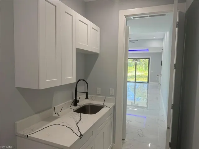 The laundry room features a sink and light tile-patterned flooring.