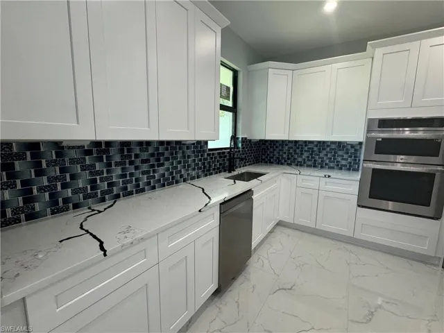 Kitchen with nice tile, dishwasher, stainless steel double oven, and beautiful backsplash with under cabinet lighting.