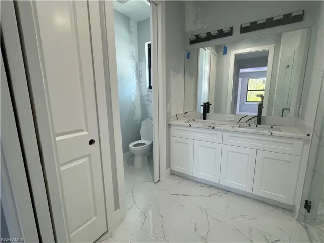 Bathroom with dual vanity, tile patterned floors, and toilet