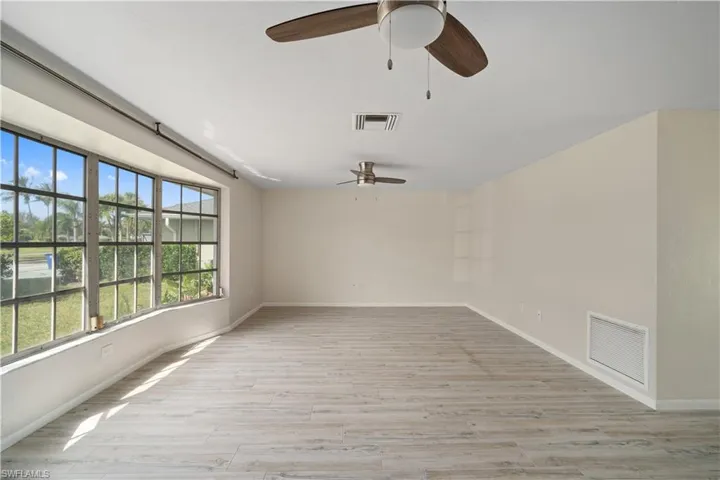 Spare room with a ceiling fan, baseboards, and light wood-style floors