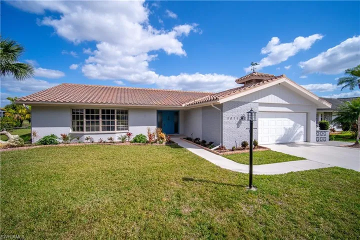 Ranch-style home with a tiled roof, a garage, a front yard, and concrete driveway