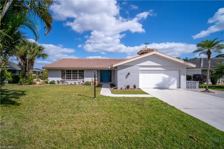 Ranch-style home with a tiled roof, an attached garage, concrete driveway, a front yard, and stucco siding