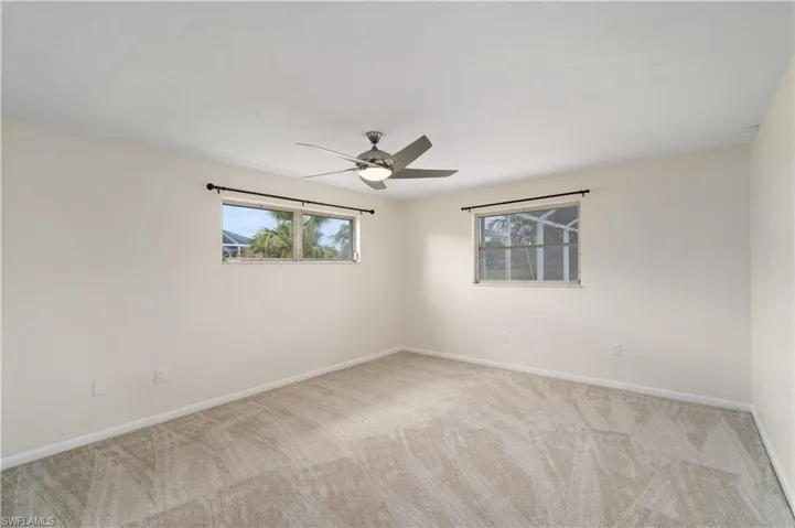 Empty room with carpet floors, ceiling fan, and baseboards