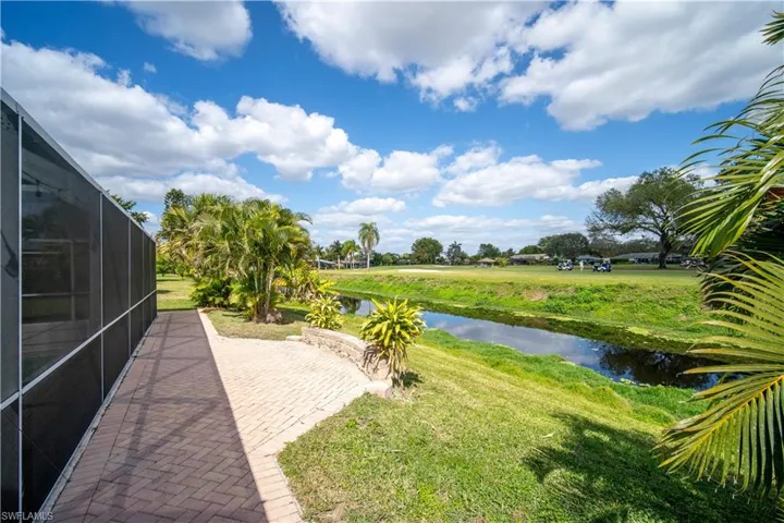 View of grassy yard featuring a water view and glass enclosure