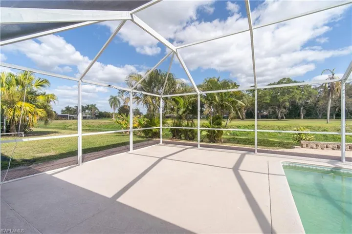 Swimming pool featuring a patio area, glass enclosure, a yard, and view of scattered trees