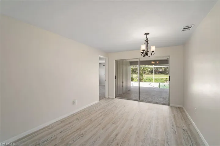Spare room featuring a chandelier, light wood-style flooring, and baseboards