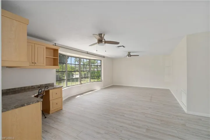 Kitchen with light brown cabinetry, a ceiling fan, dark countertops, and open shelves