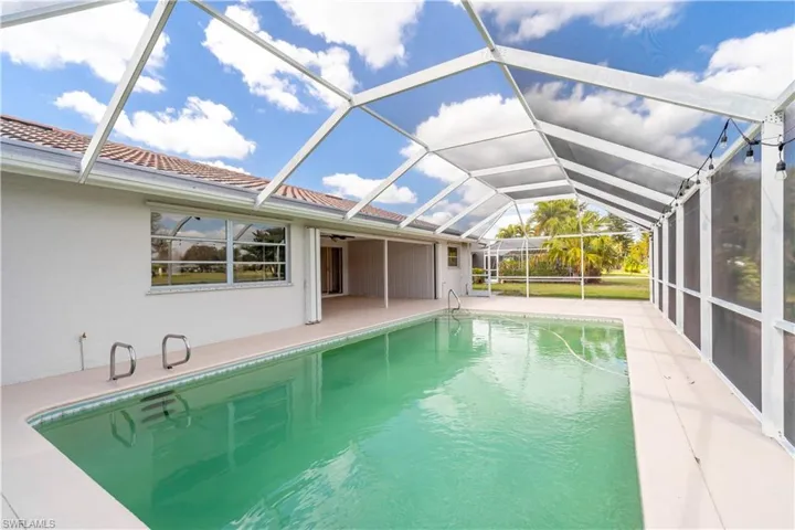 Outdoor pool featuring a patio area, glass enclosure, and a ceiling fan