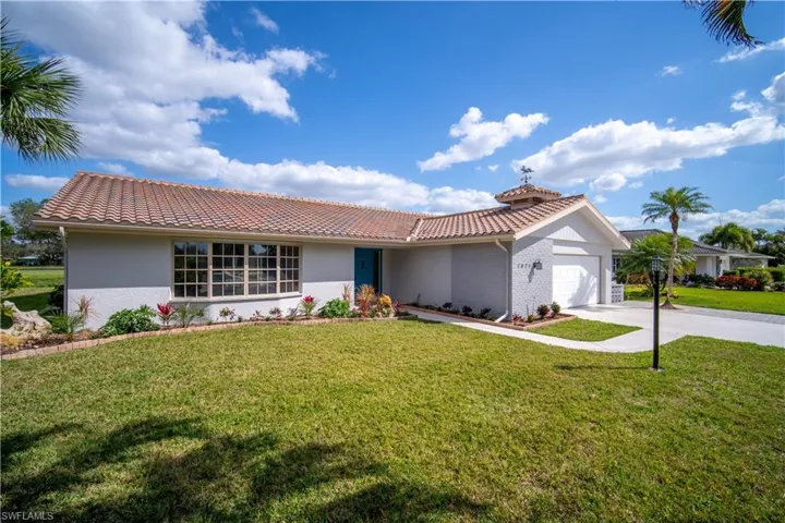 Single story home featuring a tile roof, an attached garage, concrete driveway, and a front lawn