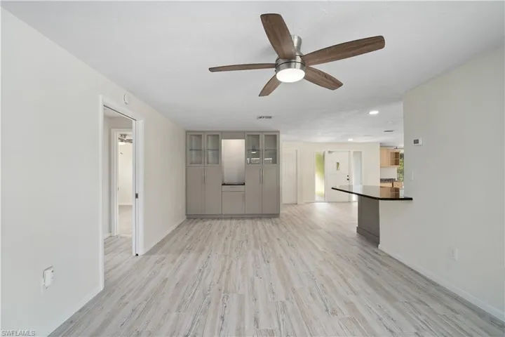 Unfurnished living room featuring a ceiling fan, baseboards, light wood-type flooring, and recessed lighting