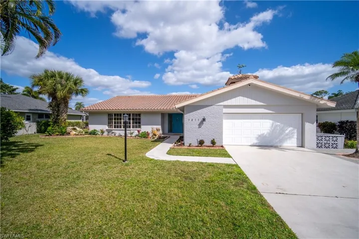 Ranch-style home with a tiled roof, a garage, a front yard, concrete driveway, and stucco siding